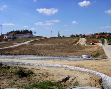 Baugebiet Büchlacker - ländliche Ansicht des abgesteckten Gebietes mit Erde und Wegen , im Hintergrund einige Häuser vor blauem Himmel